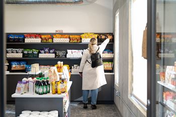 A woman in a white coat is shopping in a grocery store.at Level, Des Moines, 50309  